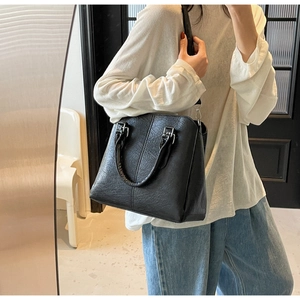 Detailed view of the textured black leather surface and metallic hardware on the handbag