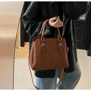 Detailed view of brown PU leather handbag featuring lychee texture and silver buckles