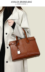 Detail of brown crocodile pattern tote bag with metal feet and decorative hardware