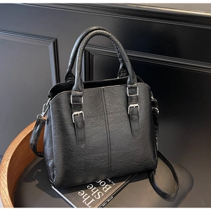 Detailed view of black litchi grain PU leather handbag with silver metal buckle accents