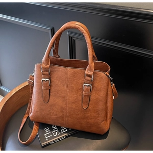 Detailed close-up of brown vintage tote bag featuring pebble grain texture and metal buckles
