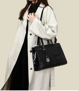 Detail of black crocodile pattern tote bag with silver rivets and metal hexagon tag
