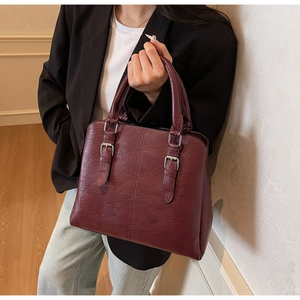 Detail of burgundy tote bag with litchi texture and silver metallic buckle detail