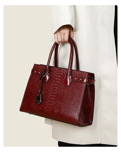 Detail of burgundy crocodile embossed tote bag featuring dual handles and metallic hardware