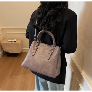 Detailed view of a taupe vintage leather handbag with silver hardware and shoulder strap
