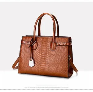 Detailed view of brown crocodile-embossed tote bag with metal tag and shoulder strap