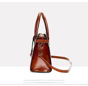 Detail view of brown leather tote bag with silver zipper and detachable shoulder strap