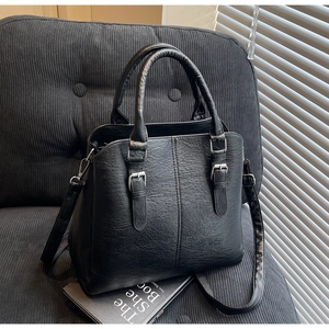 Close-up of black PU leather texture and silver buckle on a stylish tote bag