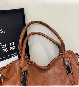 Close-up of brown leather tote bag showing handle details and metal hardware buckle