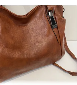 Detail showing soft brown PU leather texture and black metal buckle on the shoulder bag