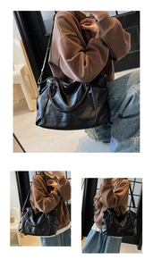Macro view of black textured leather tote bag with dual handles and adjustable strap