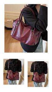 Detail view of large burgundy tote bag with adjustable shoulder strap and metal zip accents