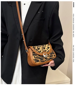 Close-up of leopard print crossbody bag with brown leather trim and silver metal buckle