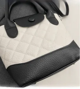 Dettaglio ravvicinato delle cuciture trapuntate e del design bicolore della borsa a secchiello