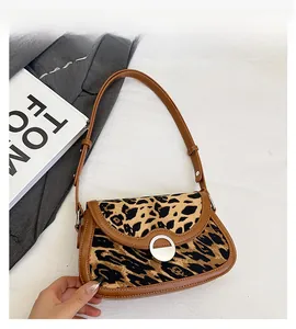 Detail view of leopard print shoulder bag with brown leather trim and silver buckle
