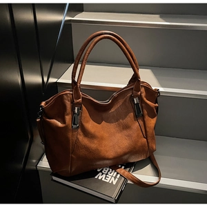 Detail of vintage brown leather tote bag on steps highlighting texture and dual handles