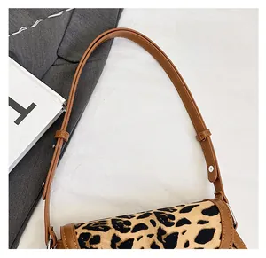 Detail of leopard print suede texture and brown leather shoulder strap with metal buckle