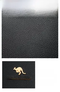 Close-up of black lychee grain leather with golden kangaroo metal logo and brand plaque