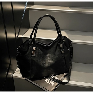 Detail of black pebbled leather tote bag with pleated design and metallic hardware