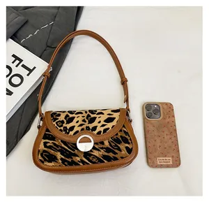 Detail view of leopard print baguette bag with leather trim and silver metal buckle