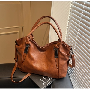 Close-up of brown leather tote bag with litchi texture and metal buckle detail