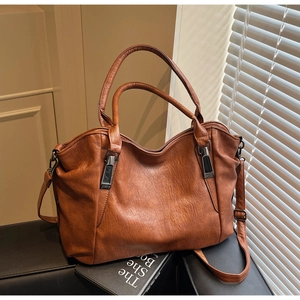 Close-up of brown faux leather tote bag texture with adjustable strap and gunmetal hardware