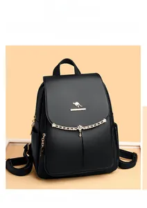 Detail view of black lychee leather backpack with golden kangaroo logo and shell chain charm