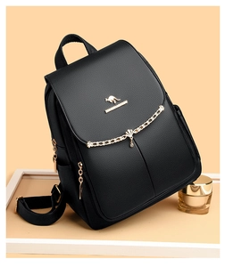 Detail of black pebbled leather backpack with gold kangaroo logo and decorative chain
