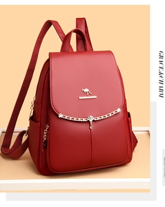 Detail of dark red pebbled leather backpack with gold kangaroo logo and metal chain decor