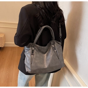 Close-up of grey leather tote bag with vintage texture and metallic side buckles