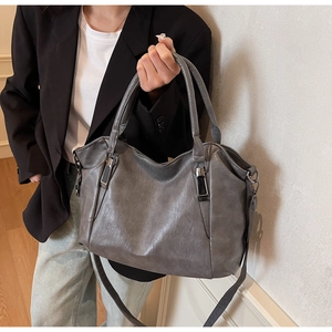 Close-up of a large grey tote bag with wrinkled texture and black metal buckles for women