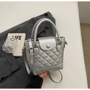 Primo piano dettagliato di una borsa a secchiello trapuntata argento su un blazer grigio