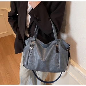 Detail of blue faux leather tote with textured wrinkles and silver metal hardware accents