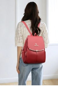 Detail view of red soft leather backpack featuring metal kangaroo logo and chain tassel