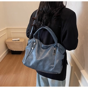 Detail view of deep blue leather tote bag showing retro pleated texture and silver hardware