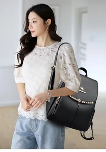 Detail of black pebbled leather backpack with gold chain and kangaroo logo on female model