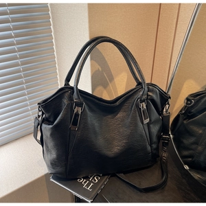 Close-up of black leather tote bag showing rich lychee grain texture and metal hardware