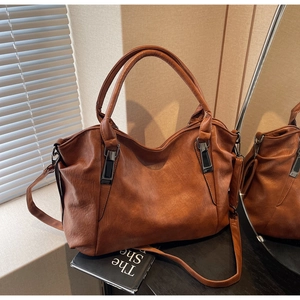 Detail of tan faux leather tote bag with metallic buckles and adjustable shoulder strap