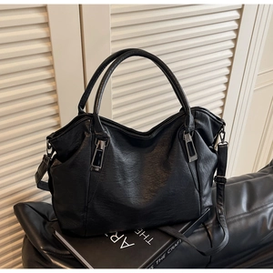 Close-up of black leather tote bag featuring dual handles and silver metal hardware