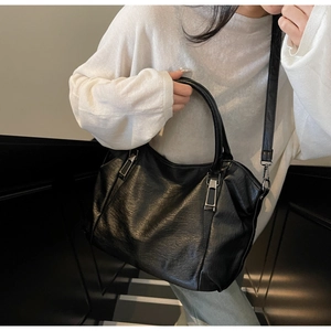 Detail of black faux leather tote with pleated texture and silver hardware details