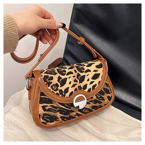 Detail of leopard print bag with brown leather trim and silver circular metal buckle
