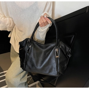 Detail of black tote bag featuring soft lychee grain texture and silver metal hardware