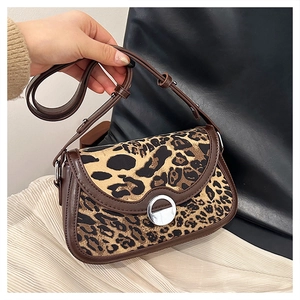 Detail of leopard print saddle bag with silver buckle and brown leather trim accents