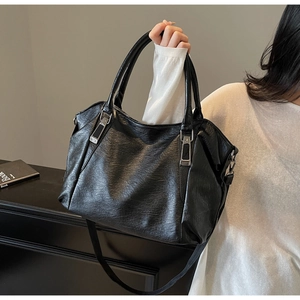 Detail of black pebbled leather tote bag with silver hardware on a display table