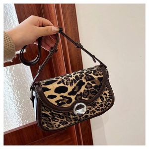 Detailed view of leopard print saddle bag with silver metal buckle and brown trim