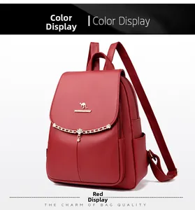 Detail of red pebbled leather backpack with gold kangaroo logo and decorative chain