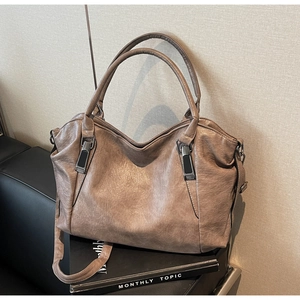 Detail of coffee brown leather tote bag with round handles and adjustable shoulder strap