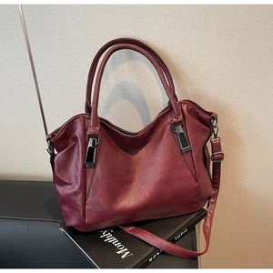 Detail of wine red leather tote bag with sturdy handles and gunmetal hardware accents