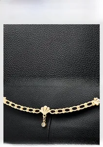 Close-up of black lychee grain leather and gold chain with shell pendant detail