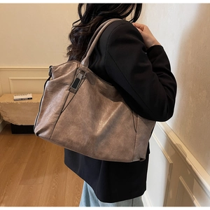 Woman carrying a grey-brown soft leather tote bag with vintage texture on shoulder